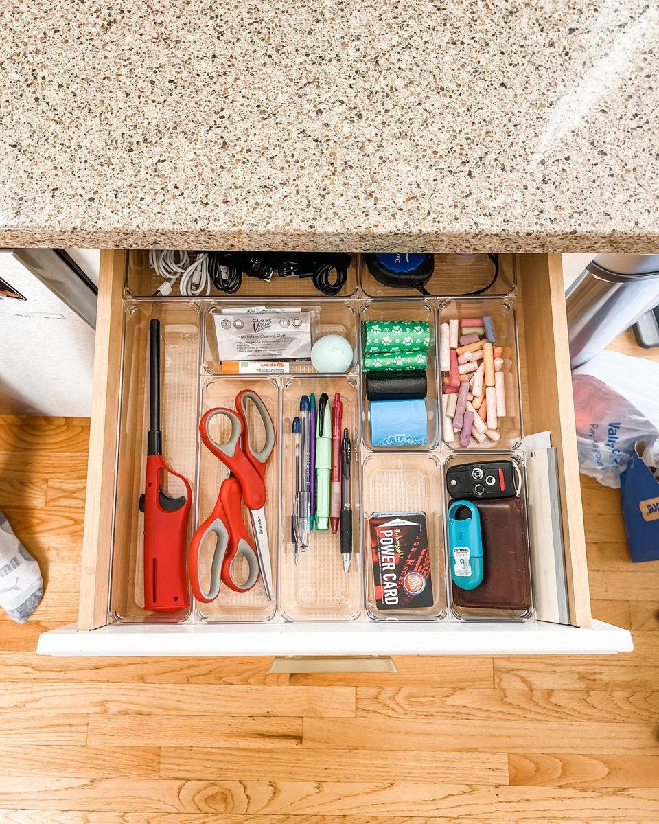 Junk drawer sorted into clear bins for cables, pens, scissors, and keys